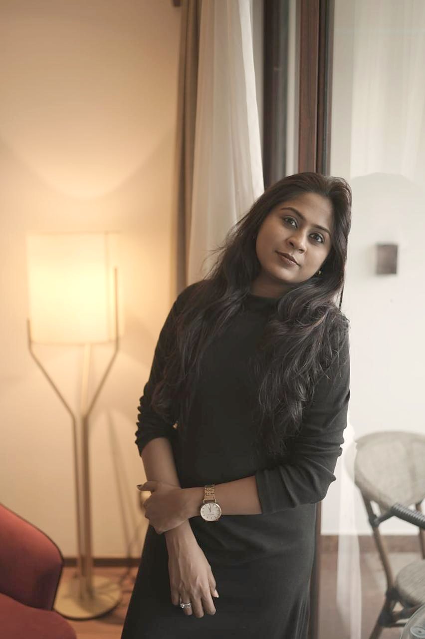 Dr. Aiswaryia Mohan in a black dress beside a warm lamp