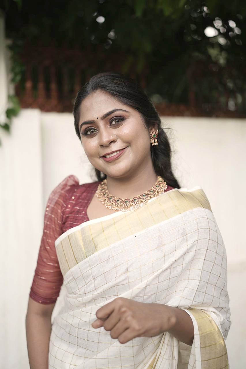 Dr. Aiswaryia Mohan smiling in a traditional Kerala kasavu saree